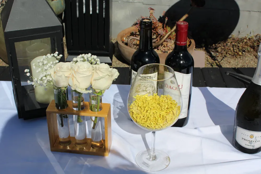 Wine, prosecco and white roses on a table on the rooftop